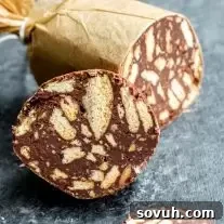 Delicious slice of Chocolate Salami with Maria biscuits visible, dusted with powdered sugar, ready to serve.