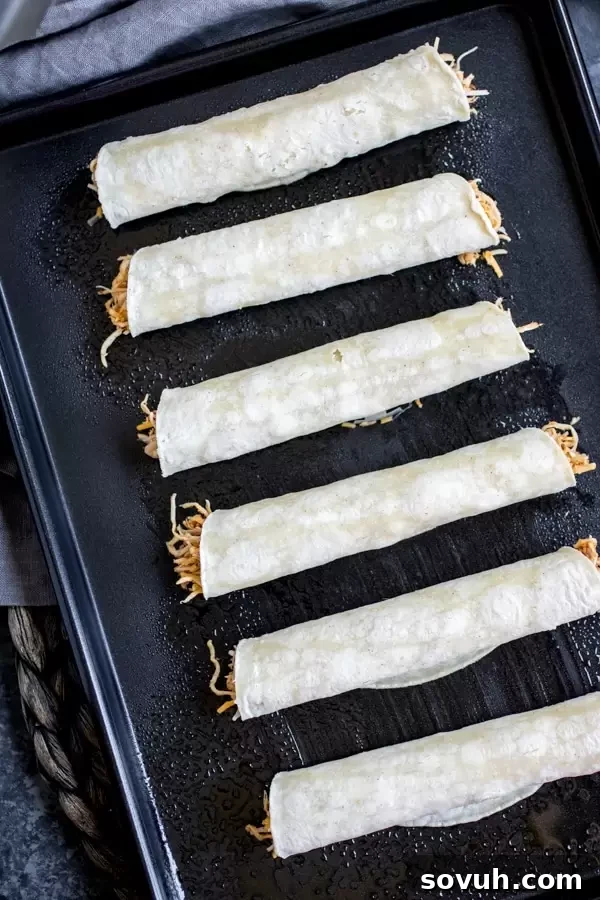 Sheet pan of golden baked Chicken Taquitos ready to be served.