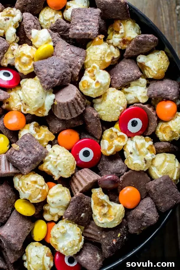 A large bowl filled to the brim with homemade Werewolf Chow, showcasing the mix of coated cereal, candies, and caramel corn.