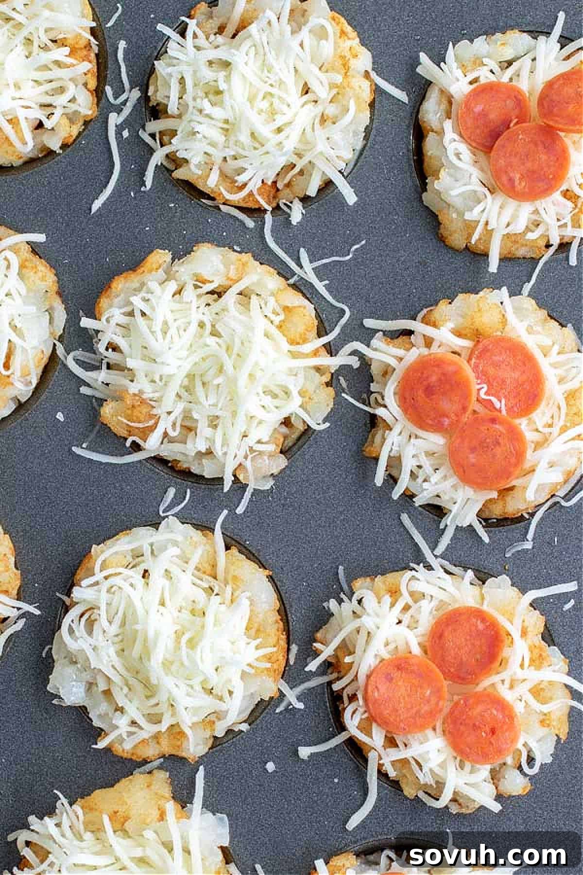 Slices of eggplant topped with cheese and pepperoni, arranged on a baking sheet.