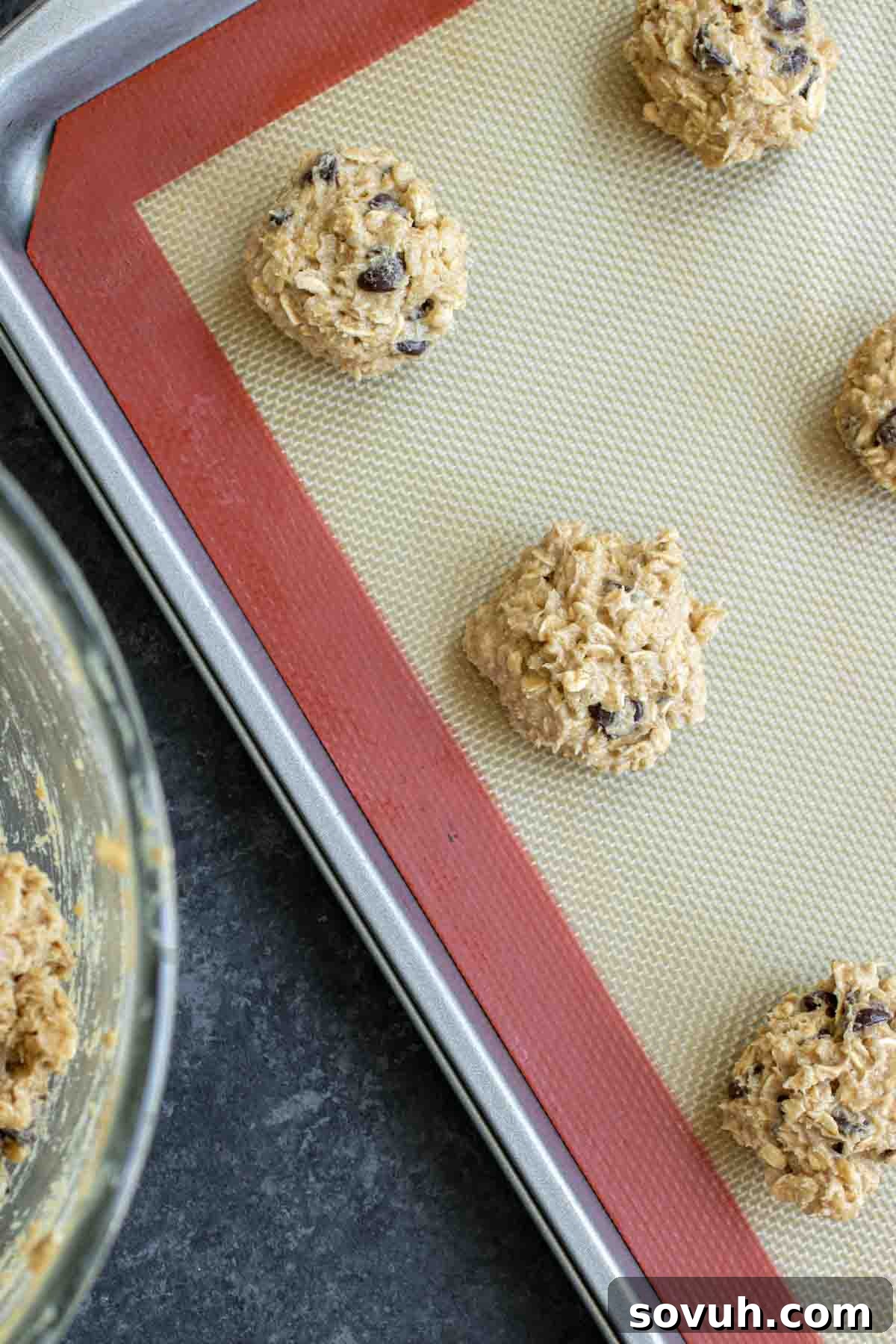 Ranger Cookies dough rolled into balls and flattened with a fork on a parchment-lined sheet pan, ready for baking