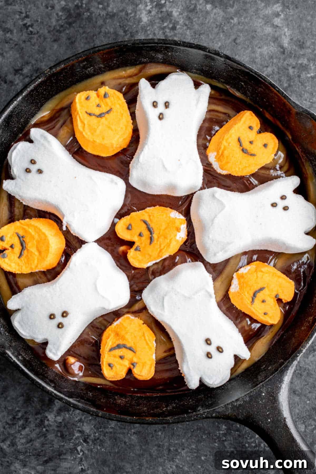 Adding festive Halloween Peeps shaped as ghosts and pumpkins to the top of the S'mores Dip.