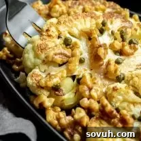 A fork lifting a piece of roasted cauliflower steaks with toasted walnuts, capers, and brown butter. A low carb, keto, and vegetarian dinner or side dish.