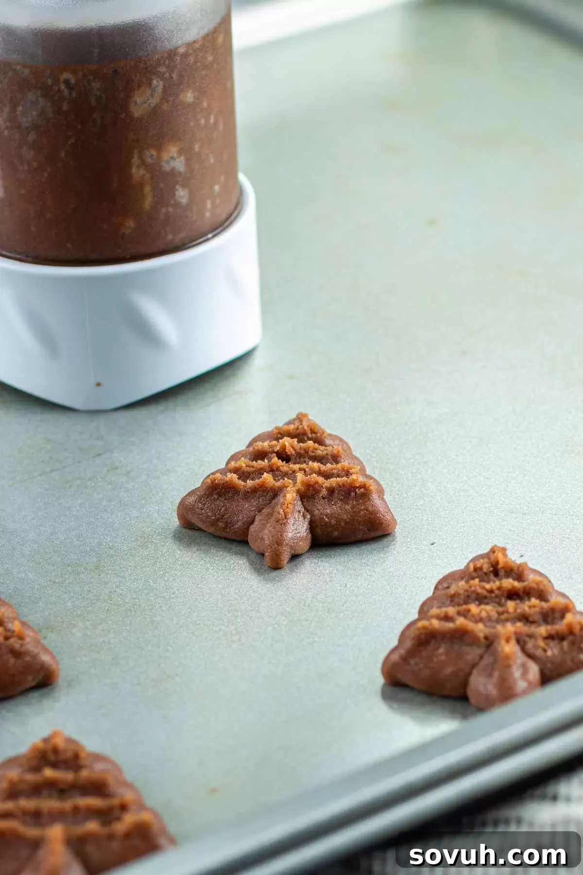 A Wilton cookie press loaded with dough, ready to make Chocolate Spritz Cookies, highlighting the essential tool for this recipe.
