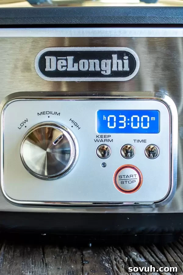 The De'Longhi Livenza Slow Cooker cooking a batch of sweet and spicy nuts, showcasing its sleek design and user-friendly controls.