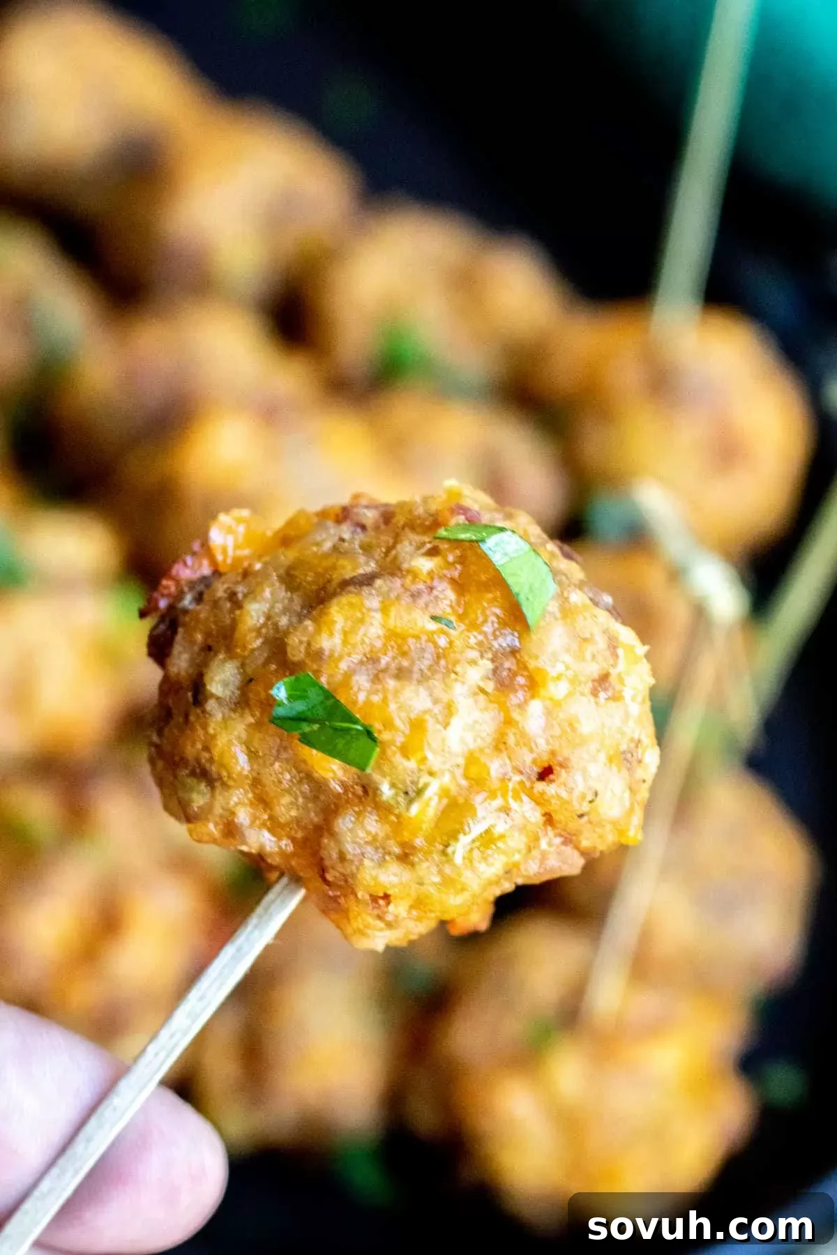 A perfectly golden Sausage Stuffing Ball on a toothpick, ready to be enjoyed, highlighting its appetizer appeal.