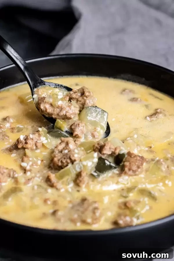 A spoonful of Instant Pot Big Mac Soup showing ground beef, cheesy broth, and diced pickles.