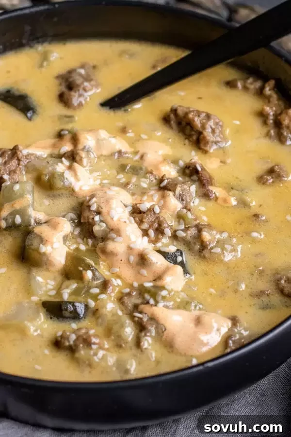 A close-up shot of Instant Pot Big Mac Soup with a vibrant drizzle of special sauce over the top.