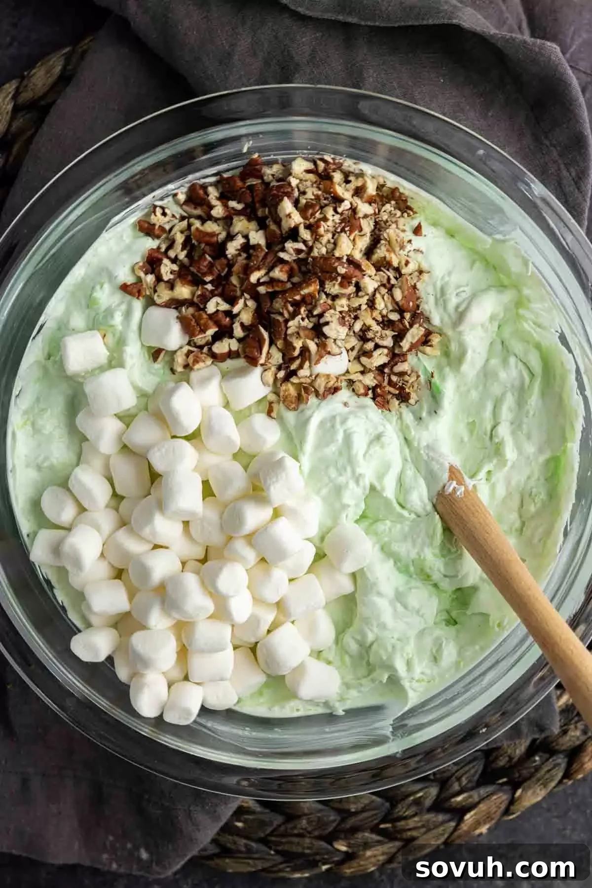 A large bowl showing the initial mixture of pistachio pudding and undrained crushed pineapple for Watergate Salad, before adding other ingredients.
