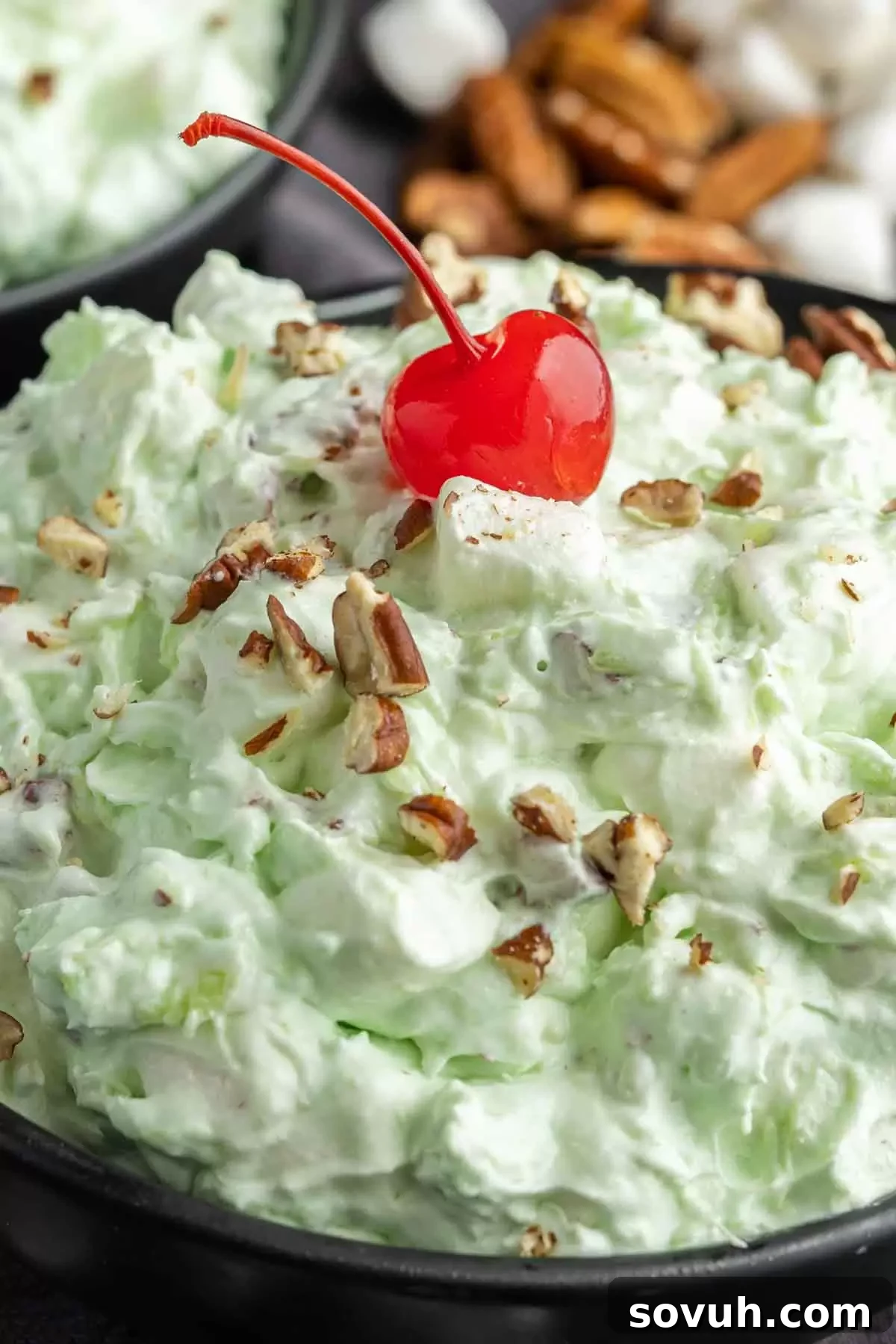 A vibrant bowl of Watergate Salad filled with mini marshmallows, crushed pineapple, and nuts, showcasing its fluffy texture.