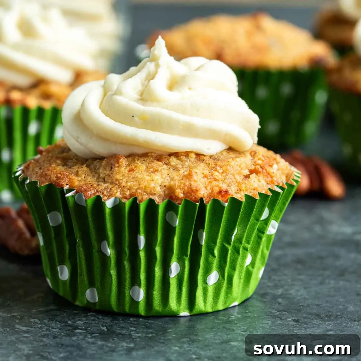 A freshly baked Keto Carrot Cake with cream cheese frosting in a vibrant green cupcake liner, ready to be enjoyed.