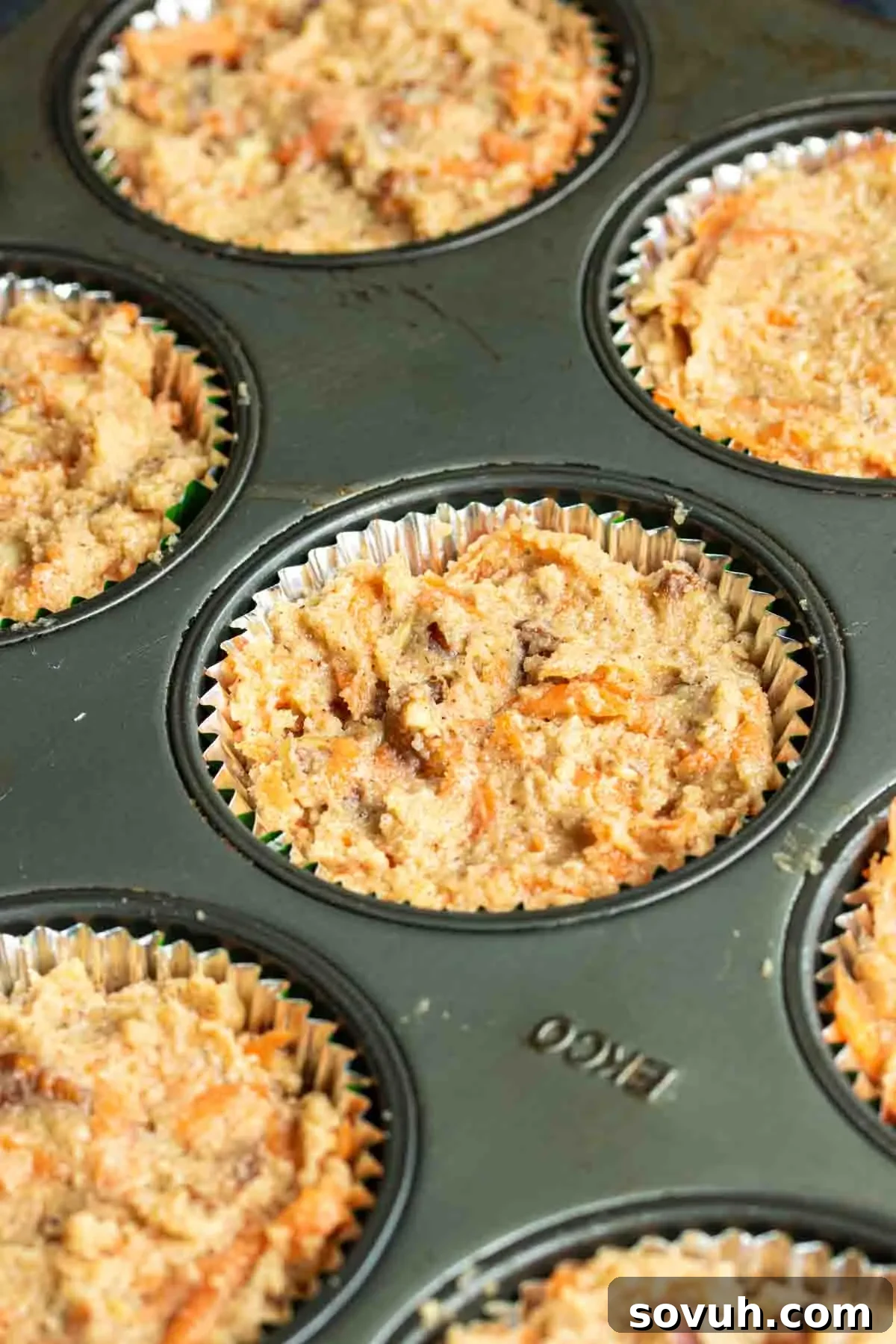 Freshly baked Keto Carrot Cake Cupcakes nestled in a muffin tin, golden brown and ready for frosting.