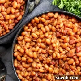 Close-up of a bowl filled with baked beans mixed with pieces of bacon or ham.