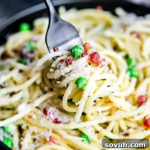 A fork twirled into a generous serving of creamy Pasta Carbonara, garnished with fresh black pepper and parsley.