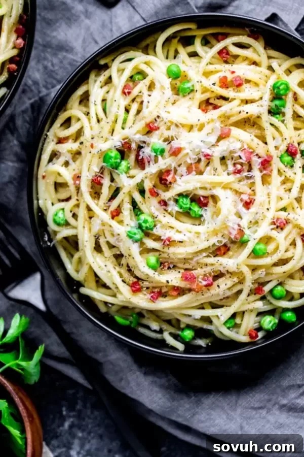 A perfectly plated bowl of creamy Pasta Carbonara, topped with extra Pecorino Romano and fresh black pepper.