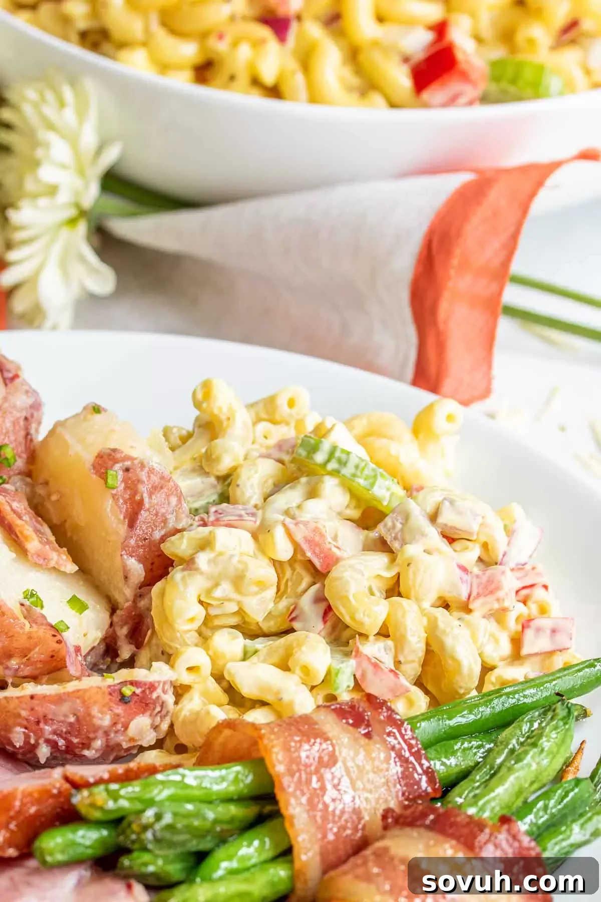 A white plate featuring a scoop of classic macaroni salad alongside other Easter dinner recipes, showcasing its role as a versatile and beloved side dish.