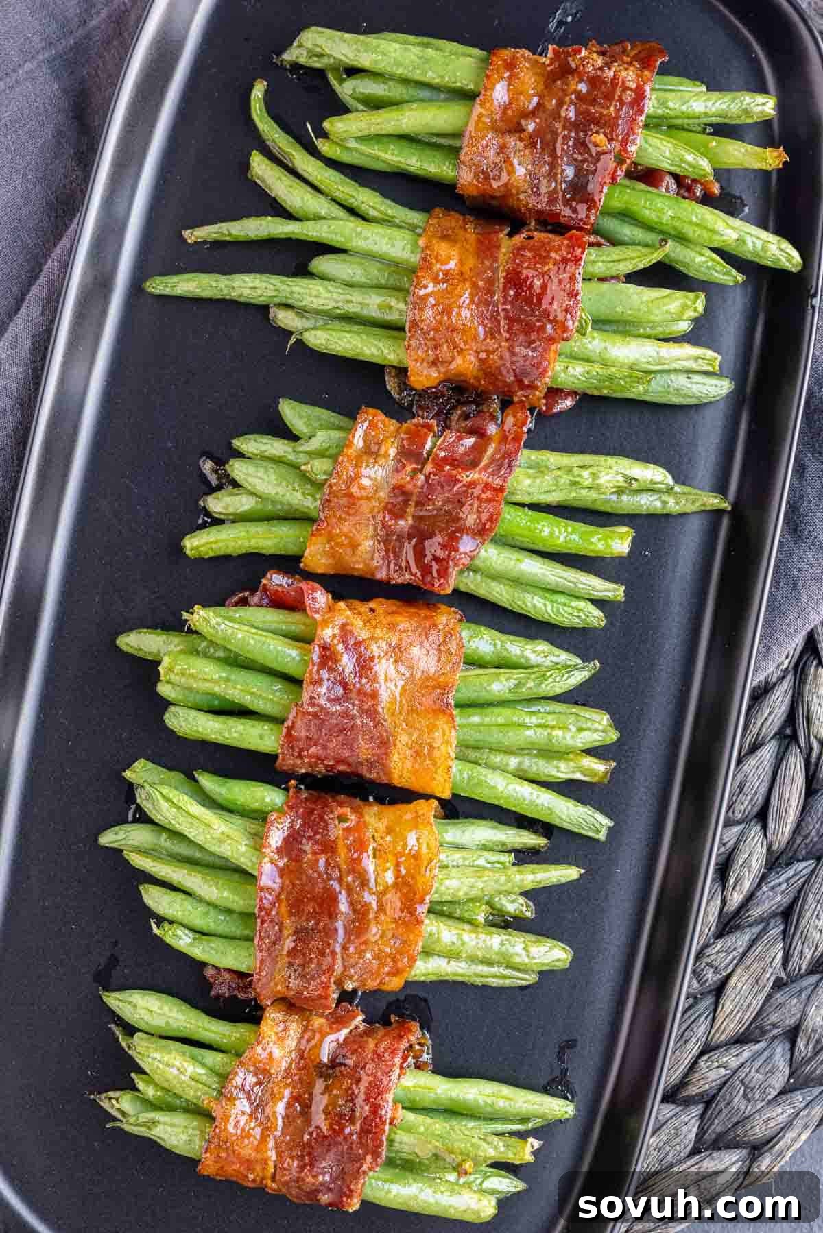 bundles of Bacon Wrapped Green Beans lined up on a black platter