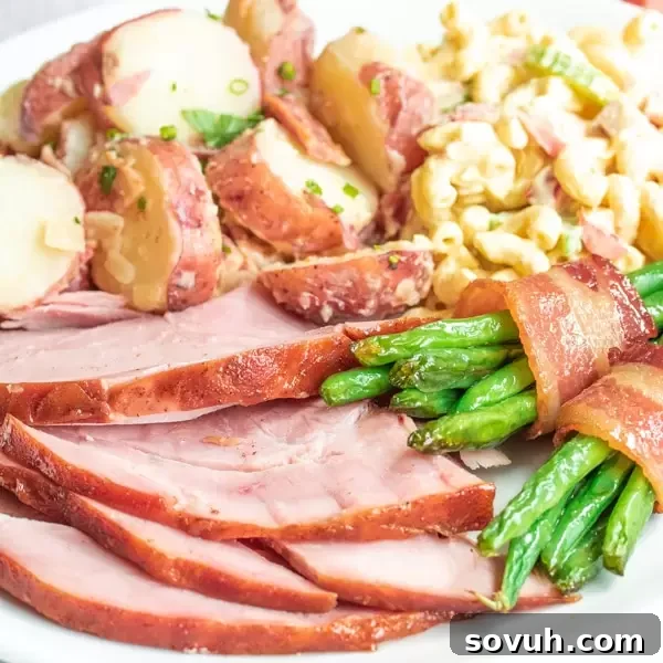 Easter dinner plate filled with honey glazed ham, green bean bundles, potato salad, and macaroni salad.