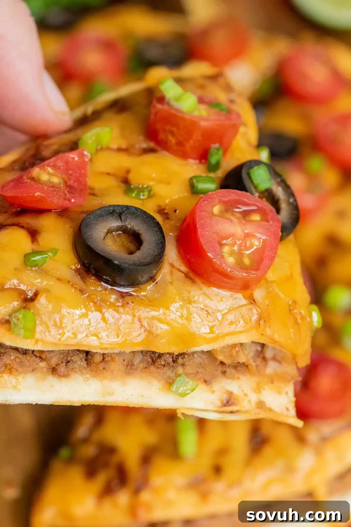 holding a slice of Taco Bell Mexican Pizza