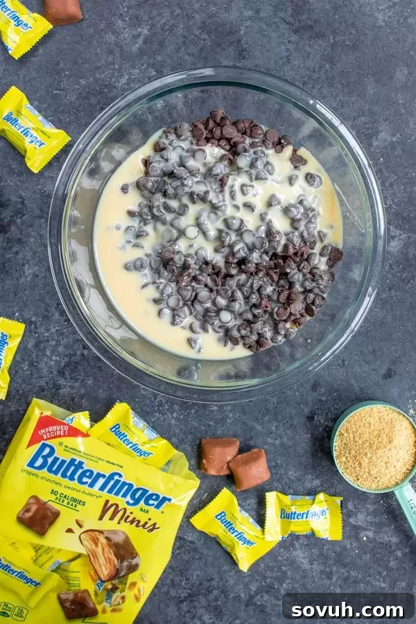 Mixing chocolate chips and sweetened condensed milk for the s'mores fudge layer in Butterfinger S'mores Bars