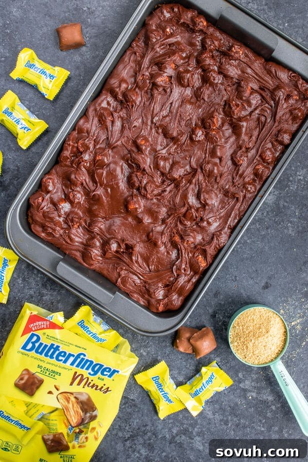 Pouring the chocolate marshmallow fudge over the baked graham cracker crust for Butterfinger S'mores Bars