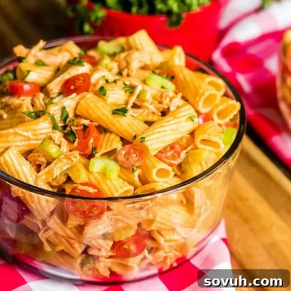 A vibrant glass bowl overflowing with Buffalo Chicken Pasta Salad, ready to be served, highlighting its fresh ingredients and creamy texture.