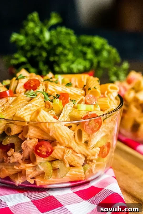 A close-up of Buffalo Chicken Pasta Salad in a glass bowl, ready to be served, showing off the rich, colorful ingredients.