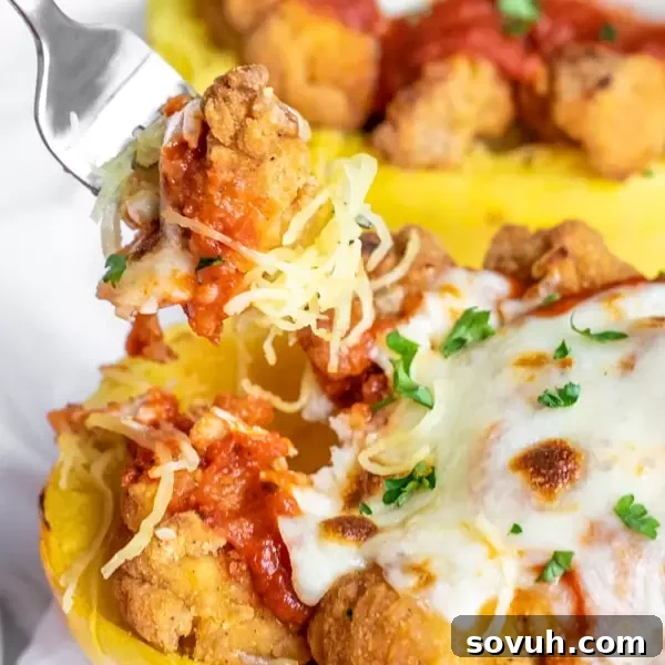 A fork digging into chicken parmesan roasted spaghetti squash, showcasing the spaghetti-like strands and cheesy topping.