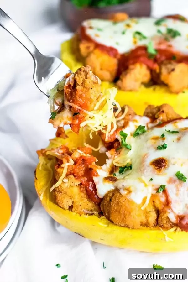 A fork taking a bite of chicken parmesan roasted spaghetti squash, showing the melted cheese and sauce.