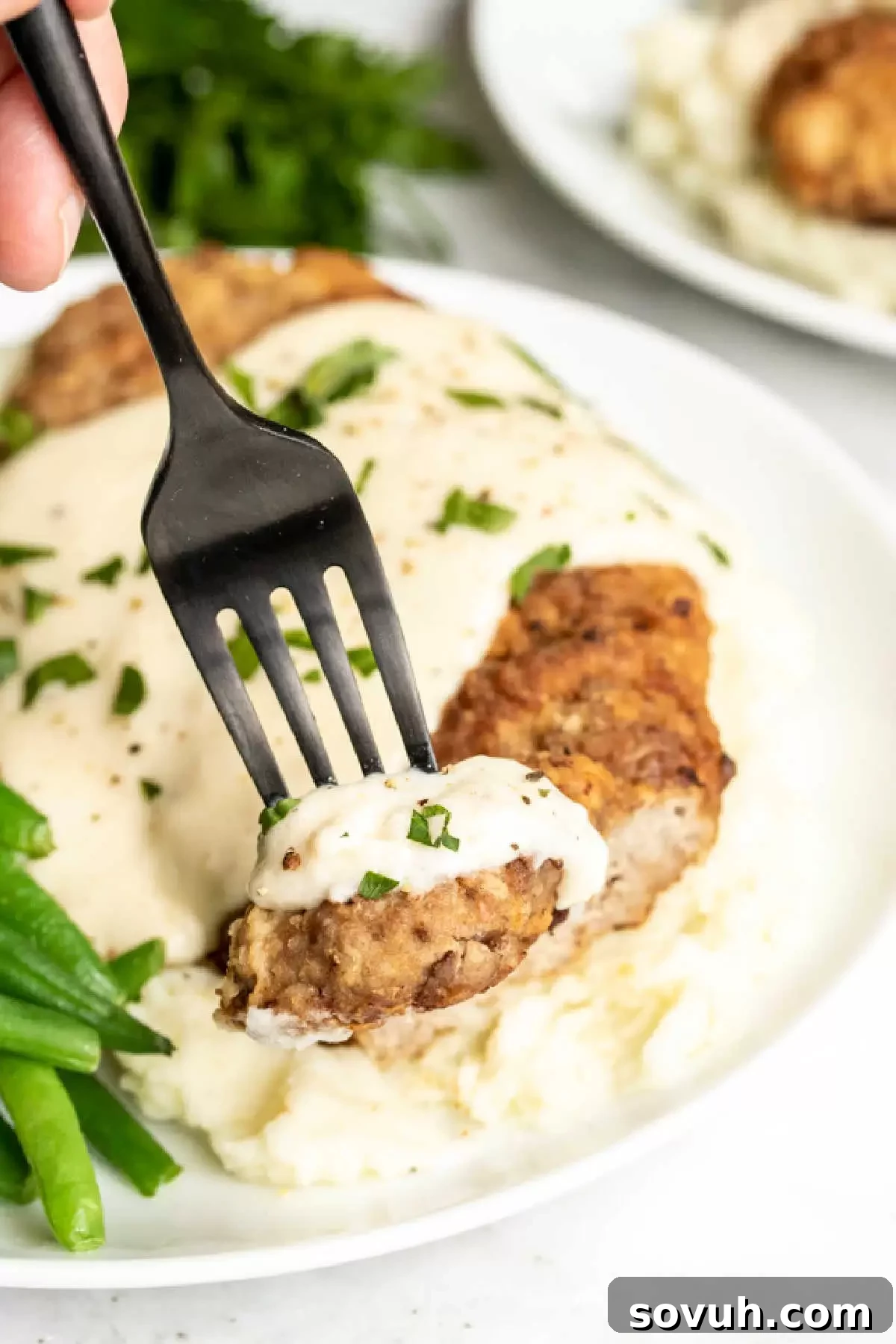 A piece of Chicken Fried Steak with Gravy on a black fork