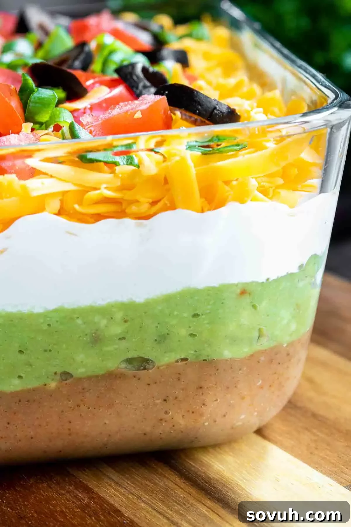 The fully assembled Mexican 7 Layer Dip in a clear glass dish, showing all layers before chilling