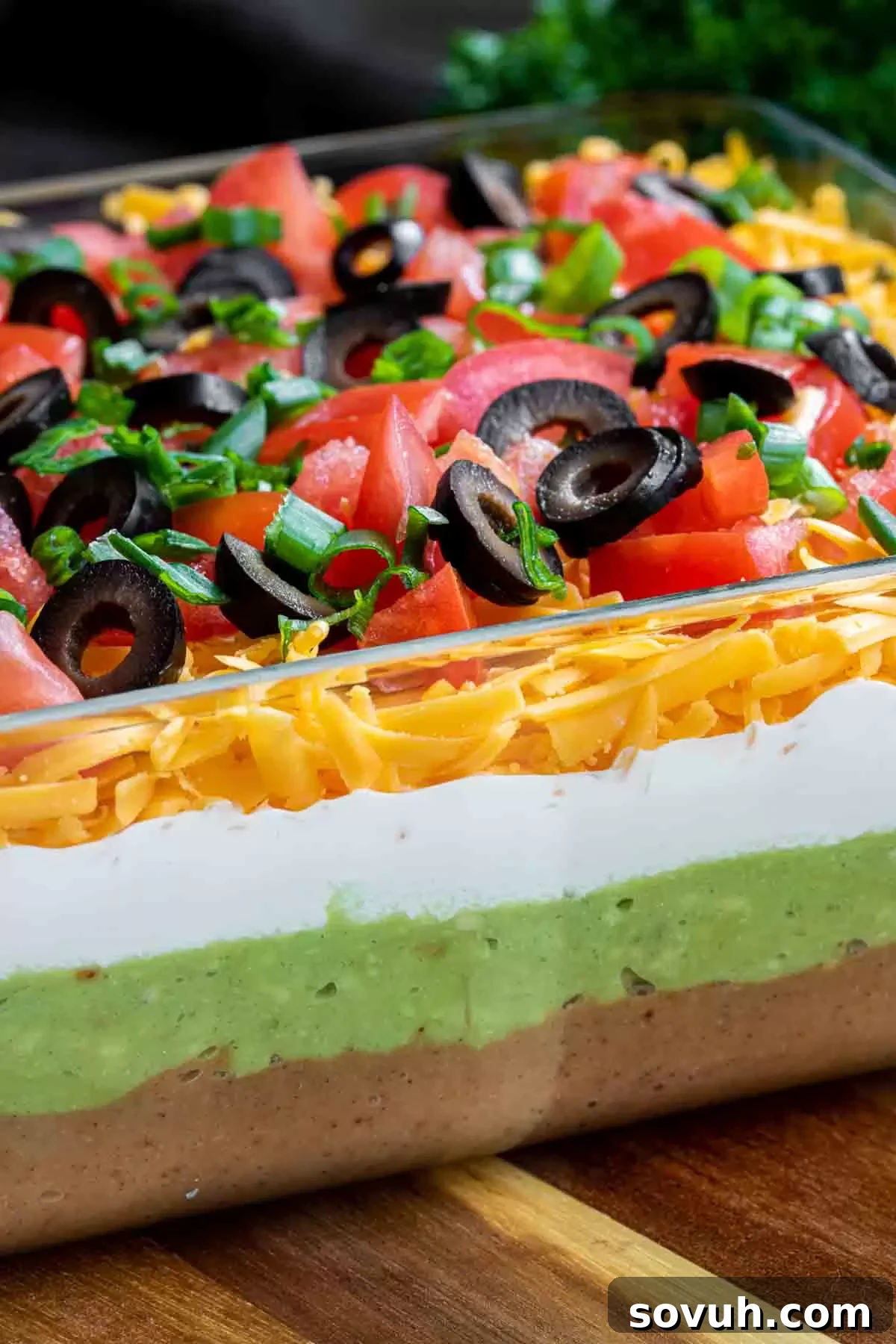 Close-up view of the 7 Layer Dip with a focus on the seasoned refried beans layer