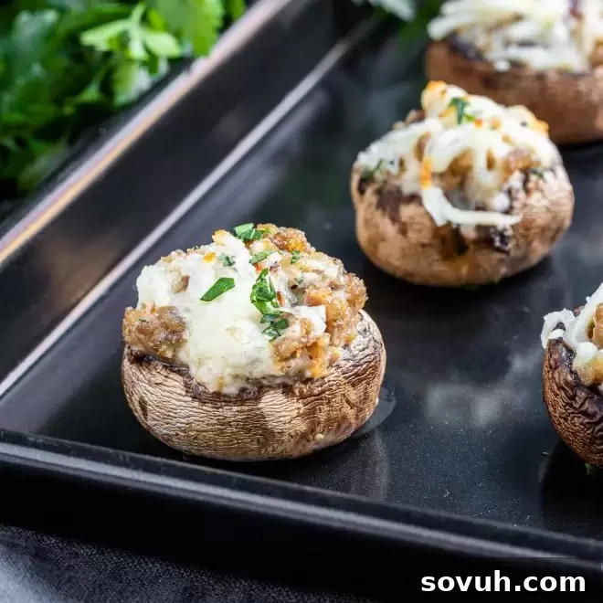 Stuffed mushrooms with sausage on a black baking sheet, ready to be served
