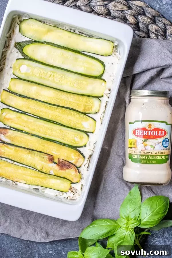 Step-by-step image showing the process of layering Chicken Alfredo Zucchini Lasagna in a casserole dish.