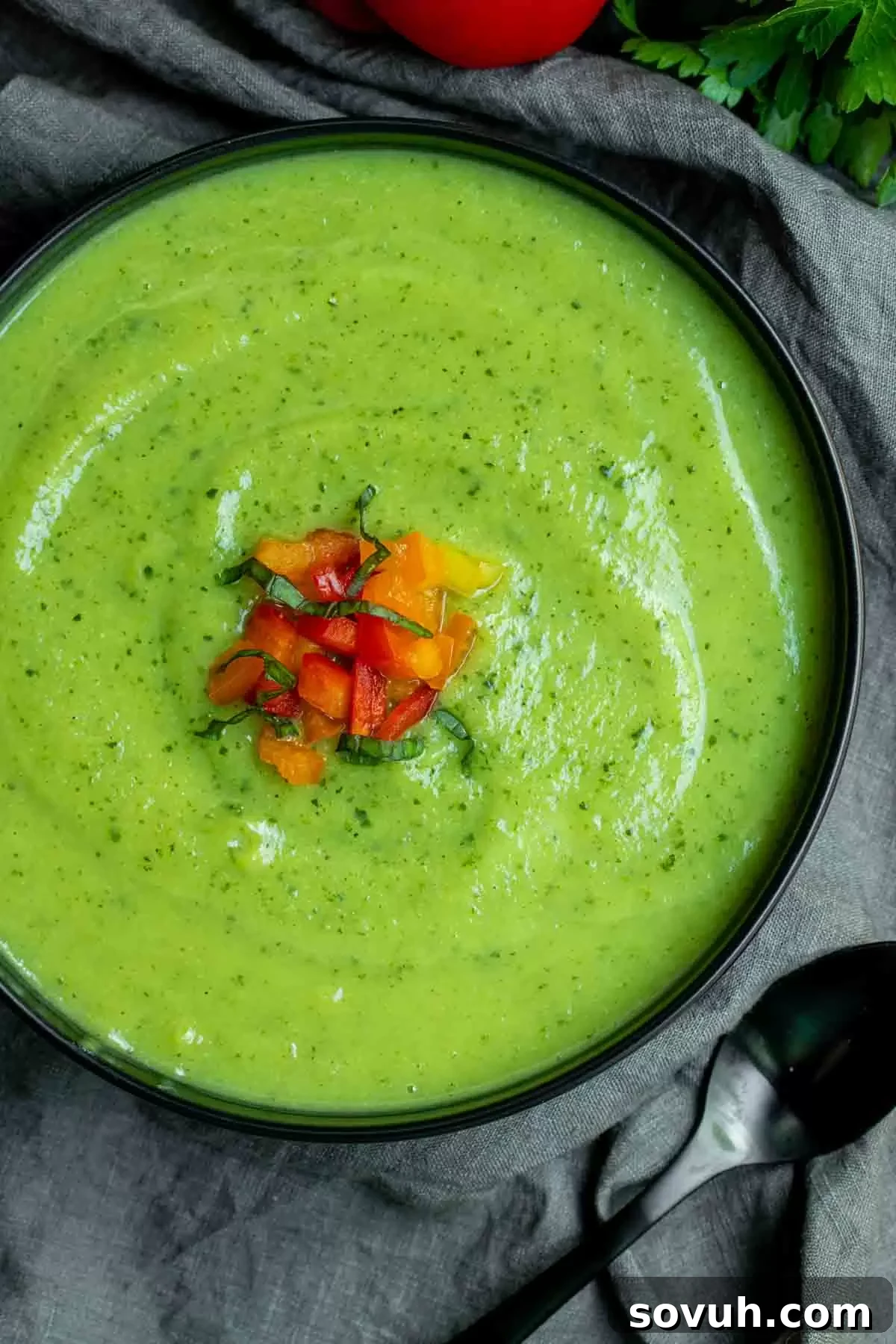 A elegant black bowl filled with creamy zucchini soup, ready to be garnished and served, showcasing its smooth texture.