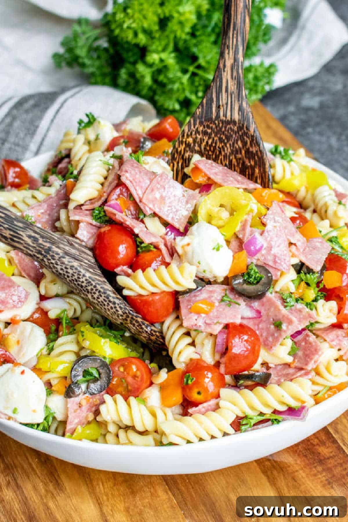 serving Italian Pasta Salad with wooden spoons in a festive outdoor setting