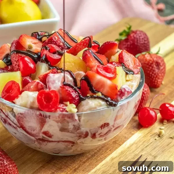 A vibrant bowl of Banana Split Cheesecake Salad drizzled with rich chocolate sauce, ready to be enjoyed.