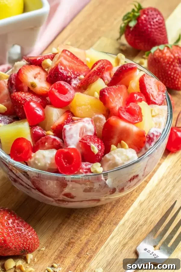 A large serving bowl filled with Banana Split Cheesecake Salad, showcasing layers of fruit and creamy dressing, waiting to be served.