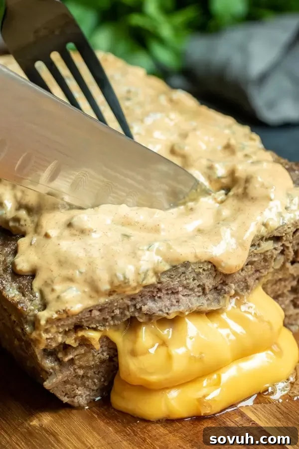 Cutting a slice of Big Mac Keto Meatloaf to reveal the melted cheese inside