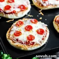 A tray of English muffin pizzas on a baking sheet.
