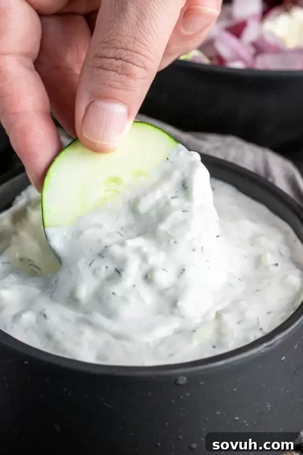 A bowl of Keto Tzatziki dip with cucumber slices arranged around it.
