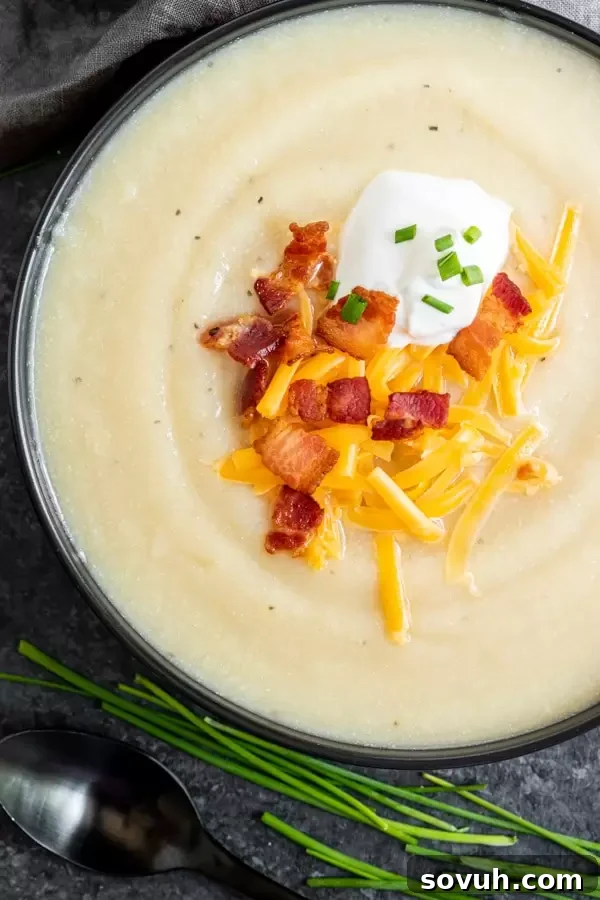 Close-up of a bowl of Instant Pot Loaded Cauliflower Soup, showing its smooth texture and rich toppings.