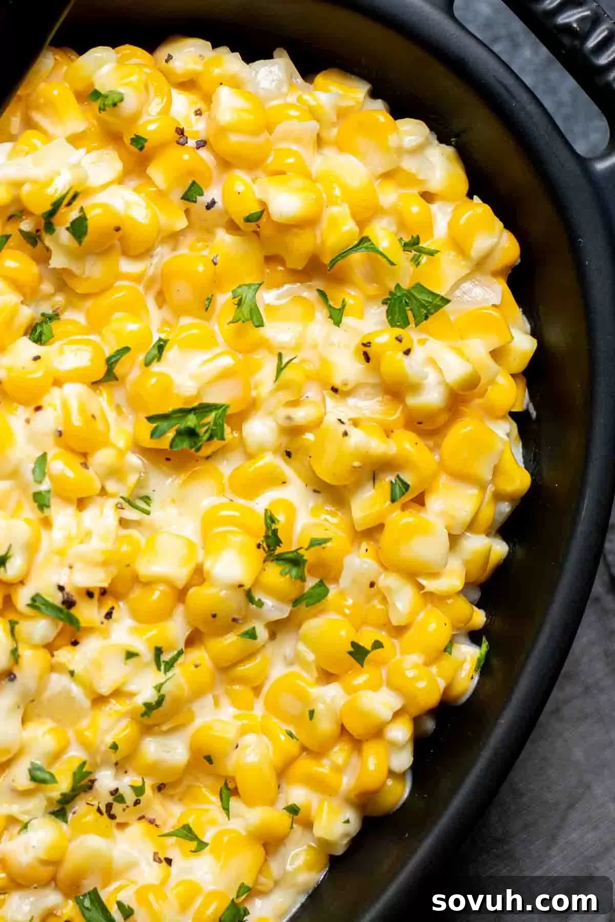 A black skillet filled with freshly made Creamed Corn, ready to be served.