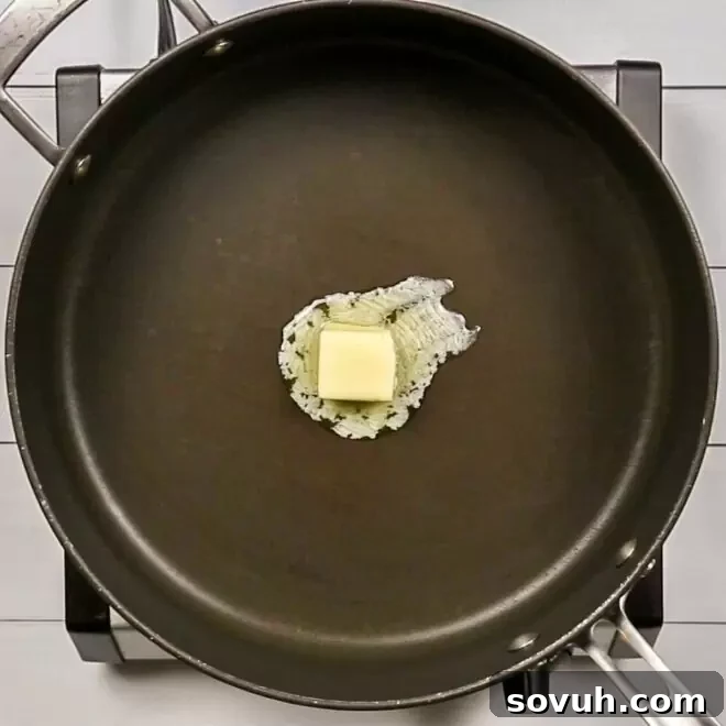 Melted butter in a frying pan on a stove top, the first step in making Creamed Corn.