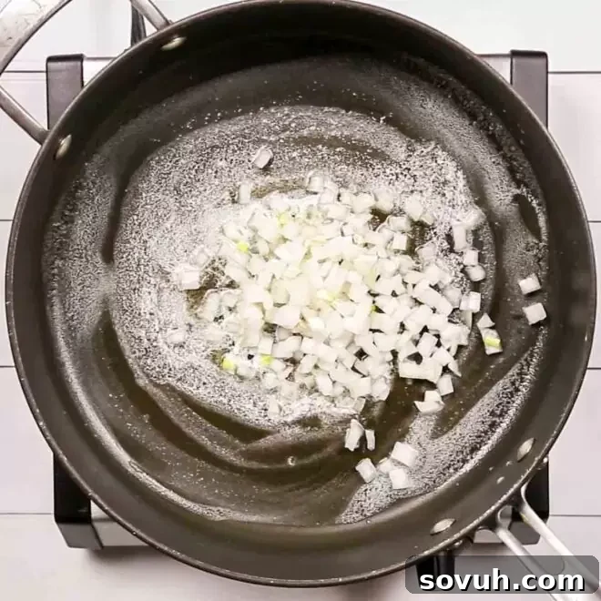 Diced onions sautéing in a frying pan with melted butter to make Creamed Corn.