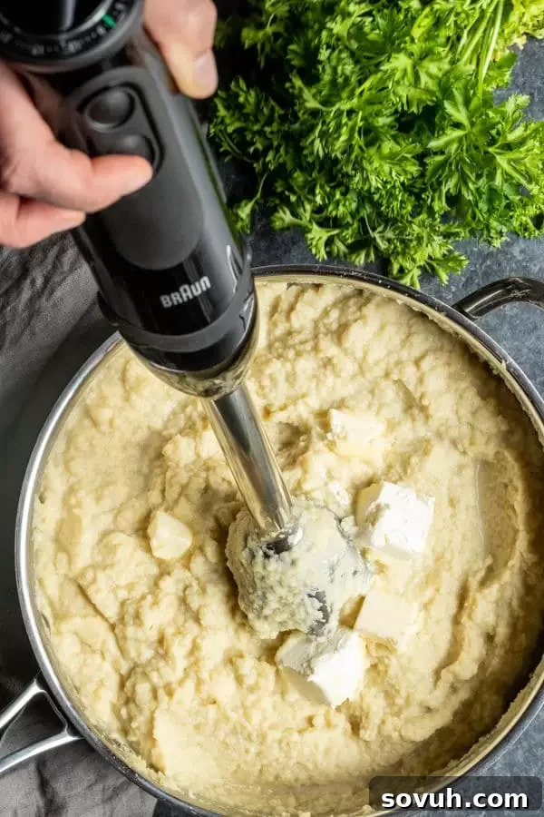 Low carb cauliflower mash with melted cream cheese, ready to be blended for Thanksgiving dinner.