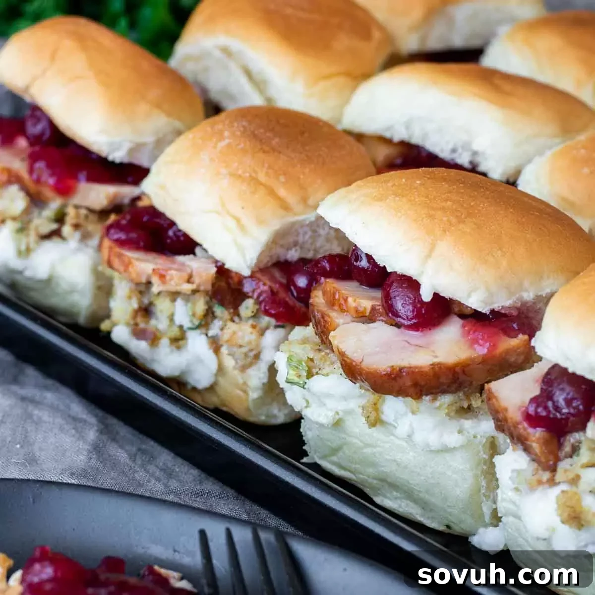 Thanksgiving Leftovers sliders piled high with turkey, stuffing, and cranberry sauce on soft rolls.