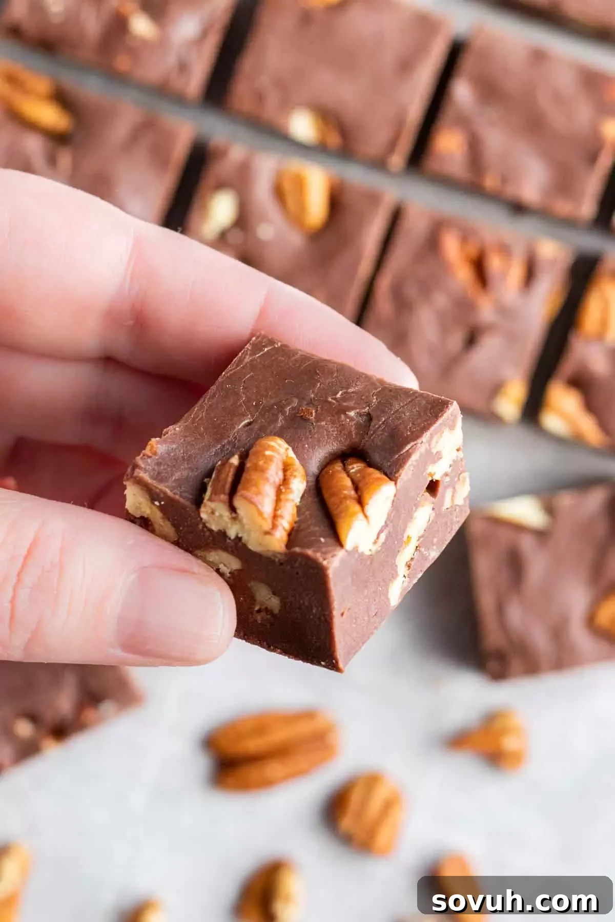 holding a piece of Easy Microwave Fudge with pecans