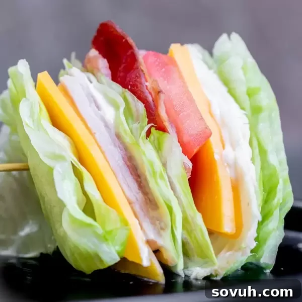 Delicious Keto Club Sandwich, layered with turkey, ham, bacon, cheese, and fresh vegetables, held together with toothpicks.
