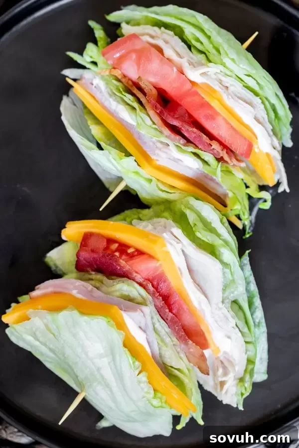 Close-up of a perfectly layered Keto Club Sandwich, showcasing fresh lettuce, turkey, ham, cheese, and crispy bacon.